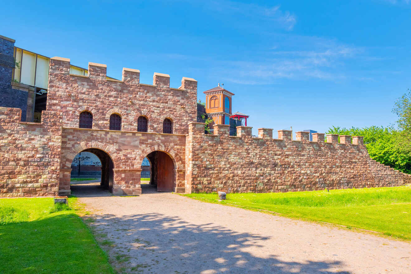 Historic Castlefield Roman Fort entrance in Manchester, with its reconstructed gatehouse and walls under a clear blue sky, symbolizing the city's ancient past